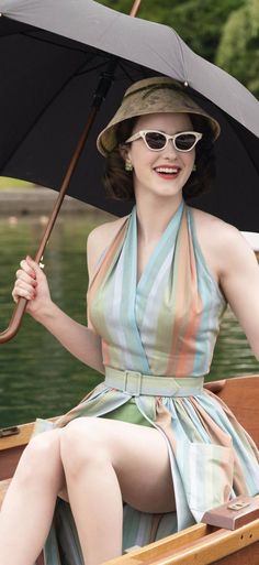 a woman sitting in a boat with an umbrella over her head and wearing sun glasses