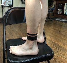 a person standing on top of a chair with a black band around their ankles and feet