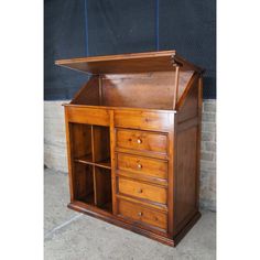 an old wooden desk with many drawers and shelves on it's sides, in front of a brick wall