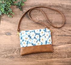 "This small crossbody bag is perfect for every day. Just the right size to carry all of your essentials hands free without weighing you down. A great addition to your wardrobe. Daisy Cross-Body Bag: Small Vegan Leather Purse ~This beautiful bag is made with a lovely canvas fabric, featuring abstract white daisies on a blue background. ~The bottom of the bag is made with faux leather in a nice warm toffee brown color. ~Entire bag is lined with a light interfacing to add durability to the bag. ~Bag is securely closed with a brass metal ykk zipper. ~Interior of the bag is lined with a heavy black canvas that will hold up well to messes, and wear and tear. ~One inside zipper pocket.  ~Long removable vegan leather strap is attached with brass color swivel hooks.   Approximate Dimensions: Width: Spring Crossbody Bag With Zipper Pouch, Spring Crossbody Shoulder Bag With Zipper Pouch, Everyday Crossbody Phone Bag With Zipper, Spring Shoulder Bag Zipper Pouch For Everyday Use, Spring Everyday Zipper Pouch Shoulder Bag, Spring Everyday Shoulder Bag With Zipper Pouch, Everyday Spring Shoulder Bag With Zipper Pouch, White Daisies, Small Crossbody Bag