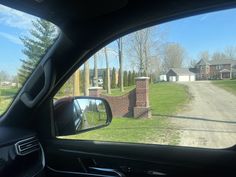 a car is parked in front of a brick house with a driveway on the other side