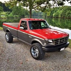 a red pick up truck parked next to a lake