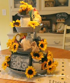 sunflowers are arranged on top of a tiered tray with chalkboards and other items