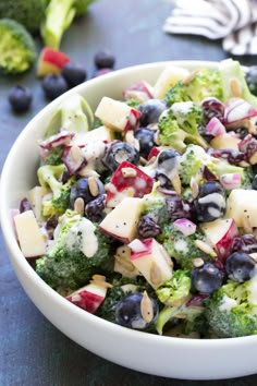 a bowl filled with broccoli, blueberries and other vegetables on top of a table