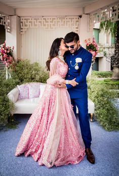 a man in a blue suit kissing a woman in a pink dress