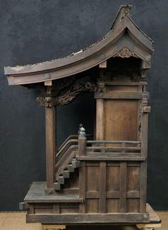 a small wooden structure with stairs and a roof on display in a museum exhibit area