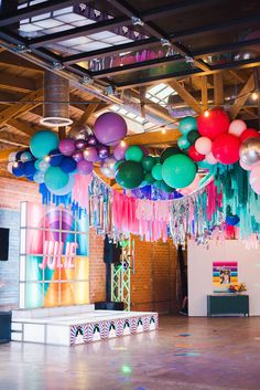 balloons and streamers are hanging from the ceiling in an open space with exposed ceilings