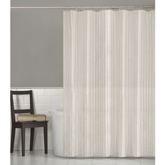 a white shower curtain next to a black chair in a gray and white tiled bathroom