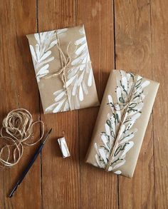 two wrapped presents sitting on top of a wooden table next to scissors and twine