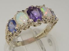 This stunning eternity ring is an ornate, handcrafted Solid Sterling Silver Victorian style design handset with a wonderful dark center Amethyst, two colorful opals and two vibrant Tanzanites. The Amethyst is oval cut and measures 7x5mm (0.28"x 0.20". The Australian Opals are 6x4mm (0.24"x0.16") in size and the Tanzanites measure 5x4mm (0.20"x0.16")The ring is adorned with ornate detailing and will come tested and Hallmarked by the London Assay Office which confirms the rings authenticity.  All Sparkly Things, Tanzanite Ring, Half Eternity Ring, Australian Opal, Multi Stone Ring, Natural Opal, The London, Victorian Style, Pink Tourmaline