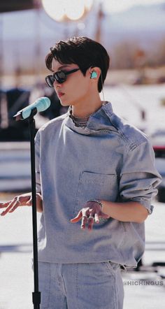 a person wearing sunglasses and holding a microphone in their hand with one hand on the mic