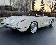 an old fashioned white car is parked on the street