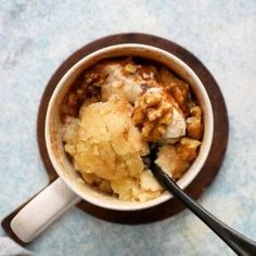 a bowl filled with food sitting on top of a table next to a cup of coffee