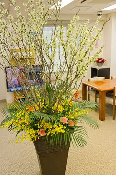 a planter filled with lots of flowers on top of a carpeted floor in an office