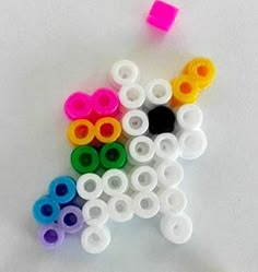 there are many different colored plastic beads on the table next to each other, including one black and one white dog