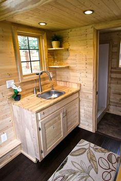 a kitchen with wooden walls and flooring next to a sink in a room that has wood paneling on the walls