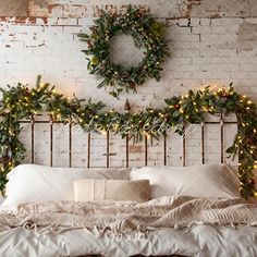 a bed with christmas wreaths on the headboard and lights hanging from the brick wall