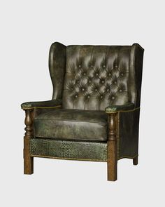 a green leather chair with wooden legs and arm rests on a gray background, it appears to be an old - fashioned piece of furniture