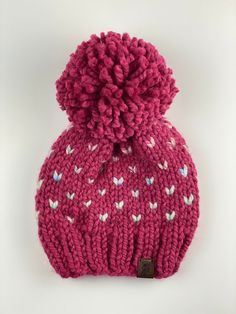 Mini Love Pom Hat (Child) - Warm, chunky, cozy knit hat - Color : Raspberry & Carousel - Material: Acrylic wool blend yarn, faux leather shop tag - Fit : Child: 19-21 inch head circumference - Care : Spot clean, lay flat to air dry - Ready to ship - If local to Des Moines area the shipping charge will be refunded and the hat will be hand delivered to the address on the order. - All sales are final.  Please contact shop with any issues.   Pattern credit Pine & Poppy Mini Love, Cozy Knit, Pom Pom Hat, Leather Shops, Des Moines, Cozy Knits, Knit Hat, Head Circumference, Air Dry