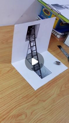 an open box with a ladder inside on a wooden table next to books and magazines