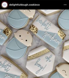 cookies decorated with blue and white icing are arranged on a marble countertop in the shape of baby's birth announcements