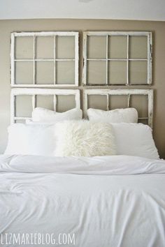 a white bed with pillows on top of it and a headboard made out of old windows