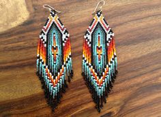 two pairs of beaded earrings sitting on top of a wooden table