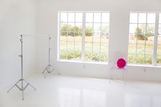 an empty room with two large windows and a pink chair in the middle, on one side