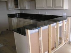 an empty kitchen with black counter tops and white cabinetry in the background, under construction