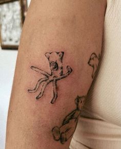 a woman's arm with an octopus and cat tattoo on the left side of her arm