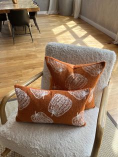 two orange and white pillows sitting on top of a chair