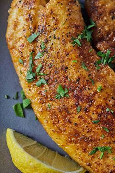 two pieces of chicken with parsley on top and the words pan fried tilapa