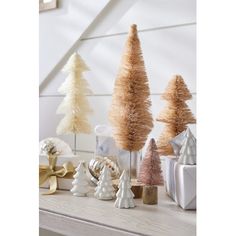 small christmas trees are sitting on a mantle in front of presents and gifts, all decorated with gold ribbon