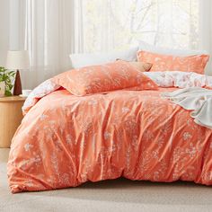 a bed with an orange comforter and pillows