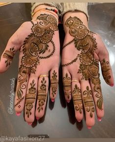 two hands with henna tattoos on them, one is showing off the intricate design