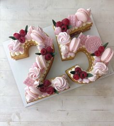 a cake shaped like the number twenty five with pink frosting and raspberries