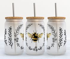 three mason jars with painted bees on them, one is gold and the other is white