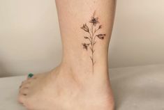 a small flower tattoo on the ankle that is black and white, with tiny flowers growing out of it