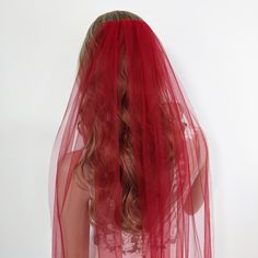 the back of a woman's head wearing a red veil over her hair and dress