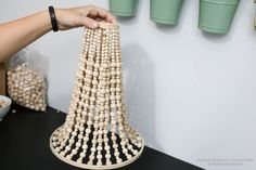 a person is holding beads in front of a tower made out of wooden balls and plastic cups