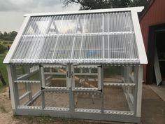 a large metal greenhouse sitting next to a red barn