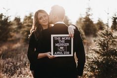 a man and woman holding a sign that says the more the merriers are