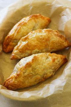 three pastries sitting on top of a piece of wax paper in a brown bowl