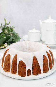 a bundt cake with white icing sitting on a plate next to some flowers