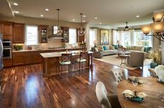 a large open concept kitchen and living room with wood flooring in an upscale home