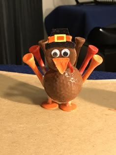 a turkey figurine wearing a thanksgiving hat and holding candy canes in its beak