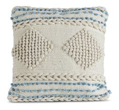 a white and blue pillow with two fish on the front, sitting on a white surface