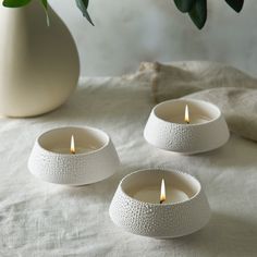 three white candles sitting on top of a table