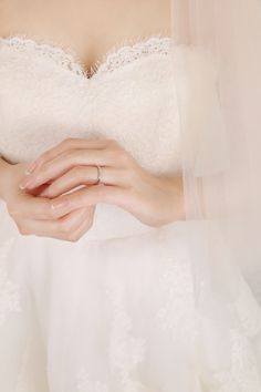 a woman in a wedding dress holding her hands together