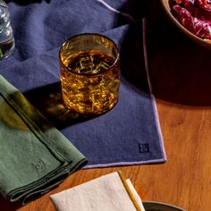 a wooden table topped with plates and bowls filled with food next to glasses of alcohol